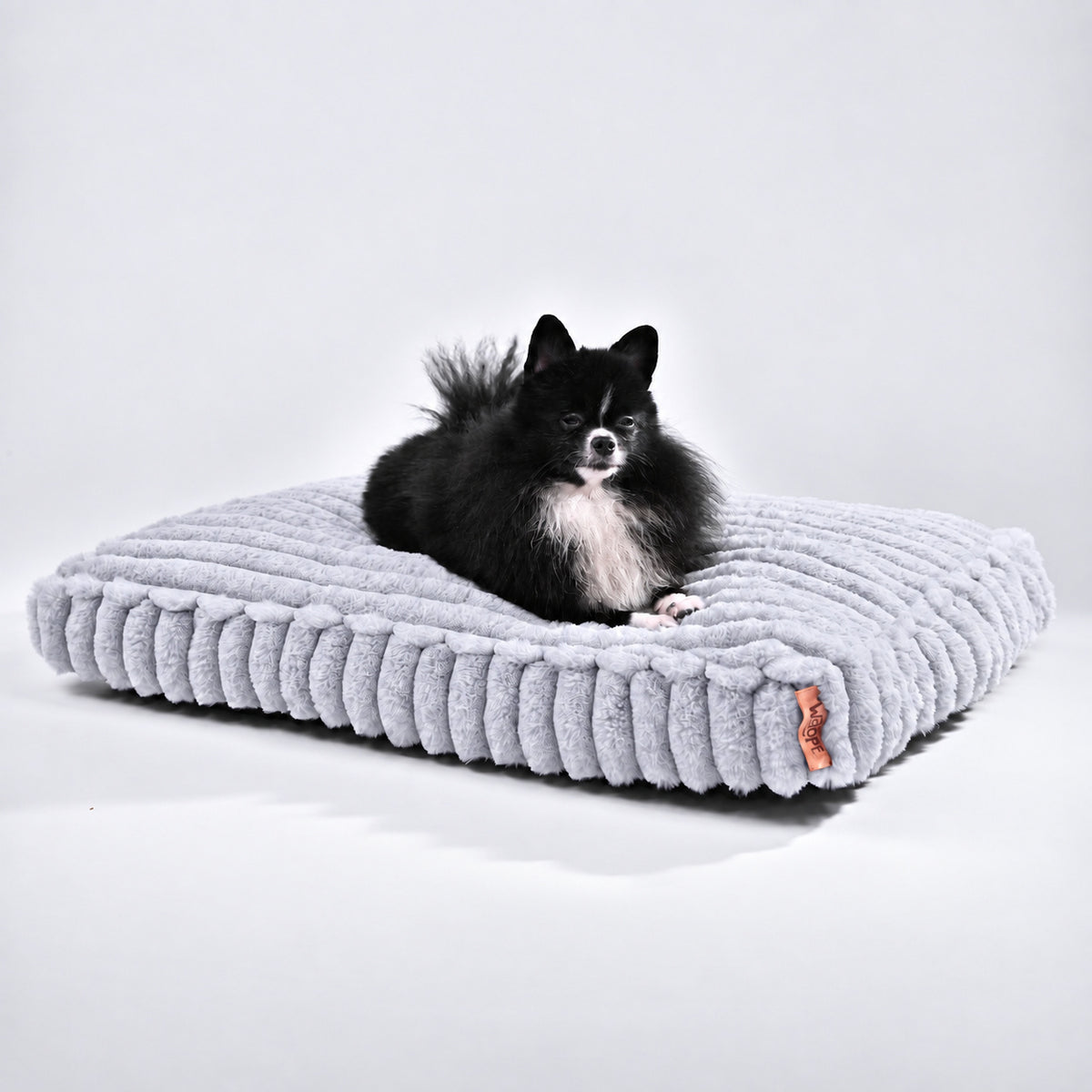 Grey | Furry Corduroy Sleeping Mat: Black and white Pomeranian lying on the Grey mat in a white studio