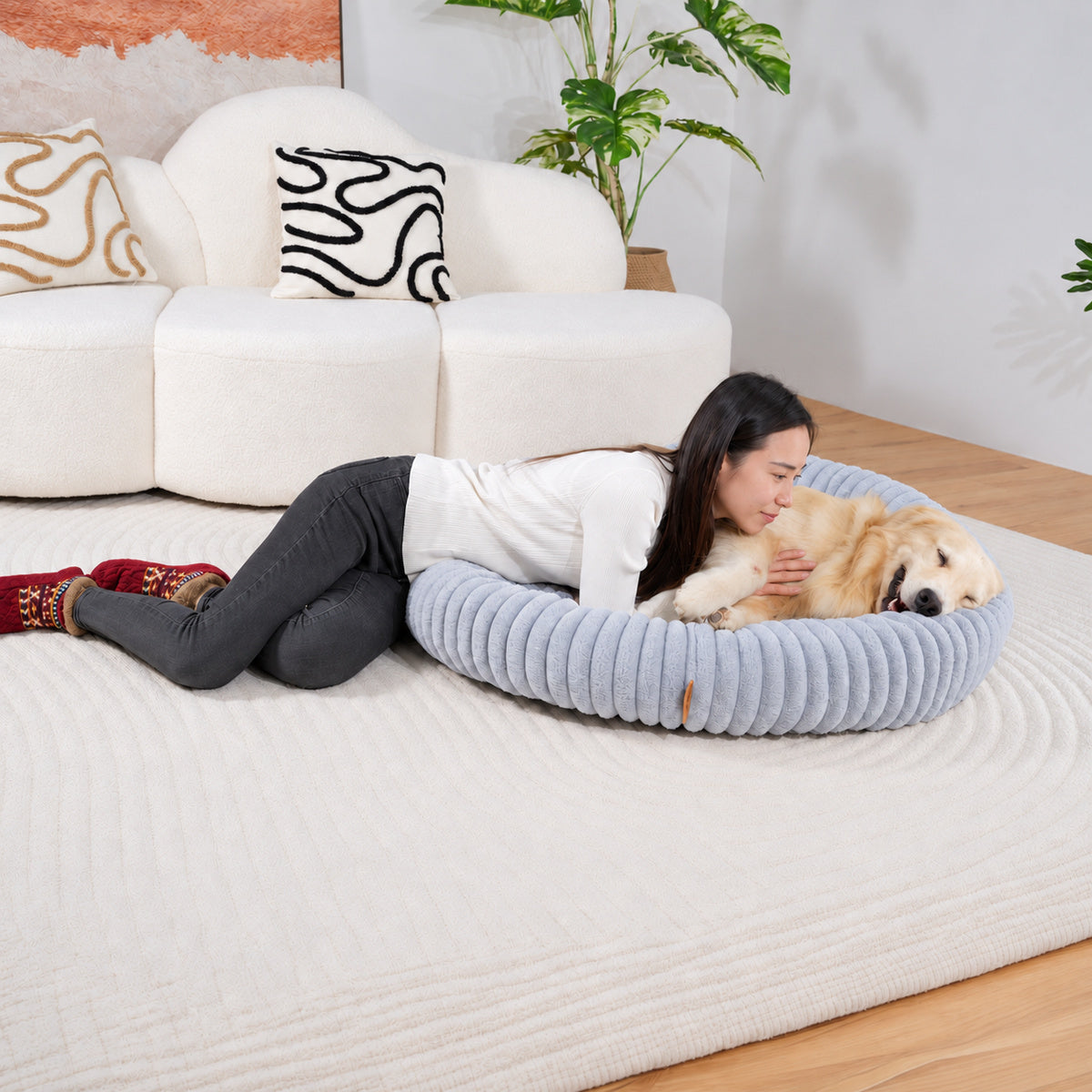 Grey | Furry Corduroy Round Bed: Woman lying beside a golden retriever in the Grey bed