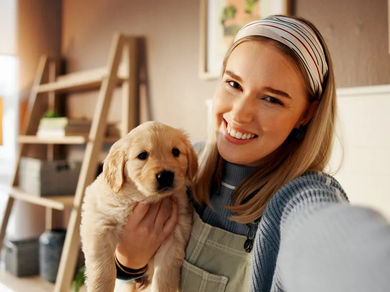 A woman taking a selfie with a golden retriever puppy